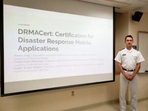 Tanner Mallari 22 stand in front of a screen showing his PowerPoint intro slide.