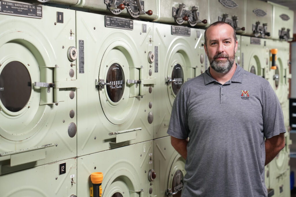 Gregory Bowman, laundry services manager at VMI, in front of washing machines.