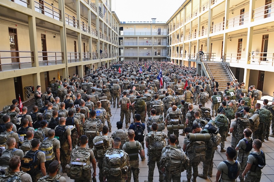 Cadets bow their heads while carrying backpacks.