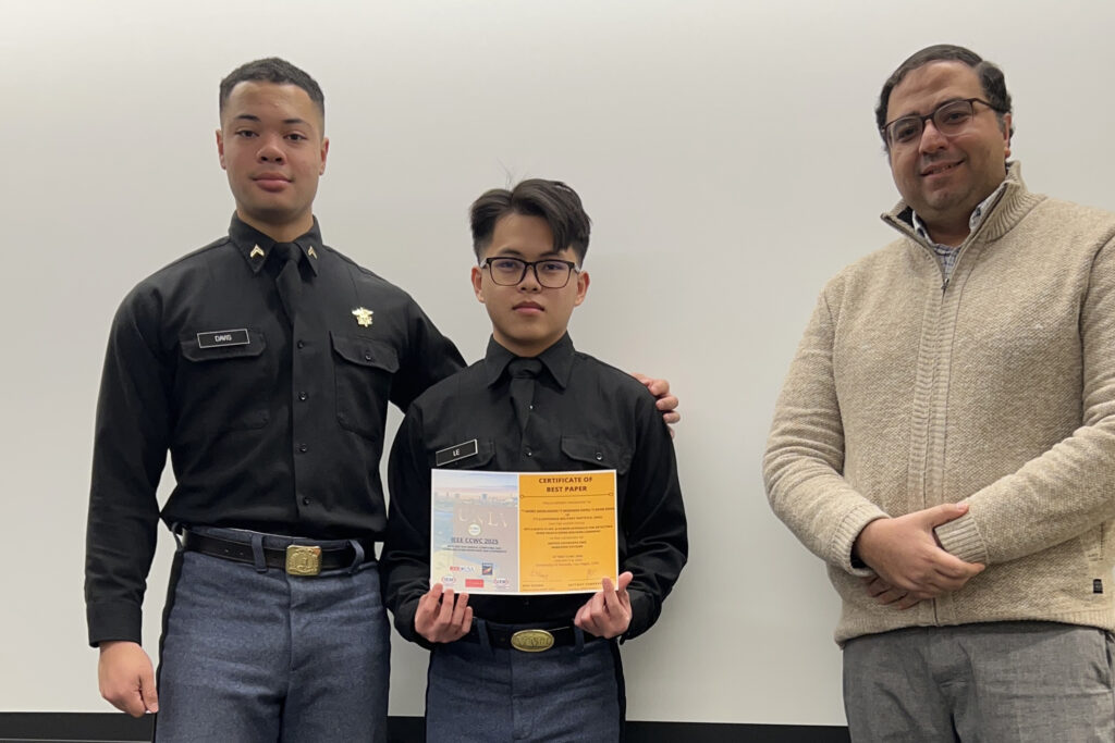 Cadet poses with certificate, fellow cadet, and professor.