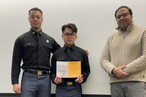 Cadet poses with certificate, fellow cadet, and professor.