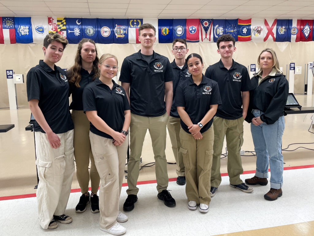 Cadets pose in team t-shirts at the shooting range.