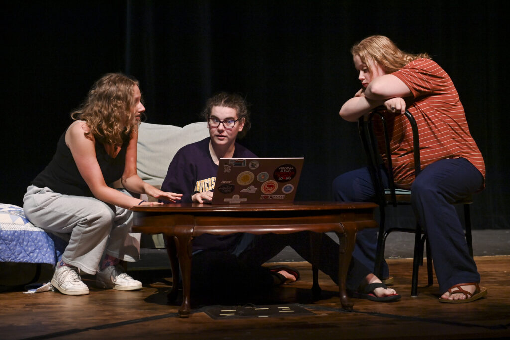 Actors on stage in living room set.