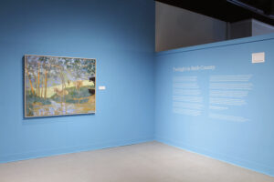A colorful landscape painting stix on an adjacent wall to Smith's poem in white text on a light blue background.