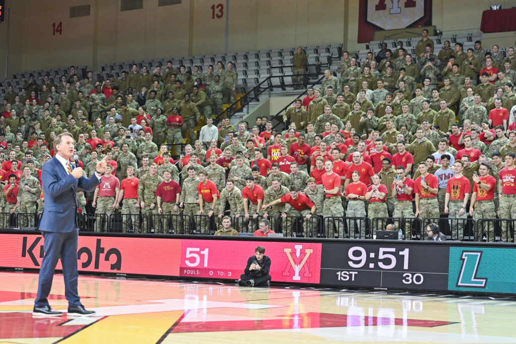 Gov. Youngkin walks on the court as cadets stand and lean in.