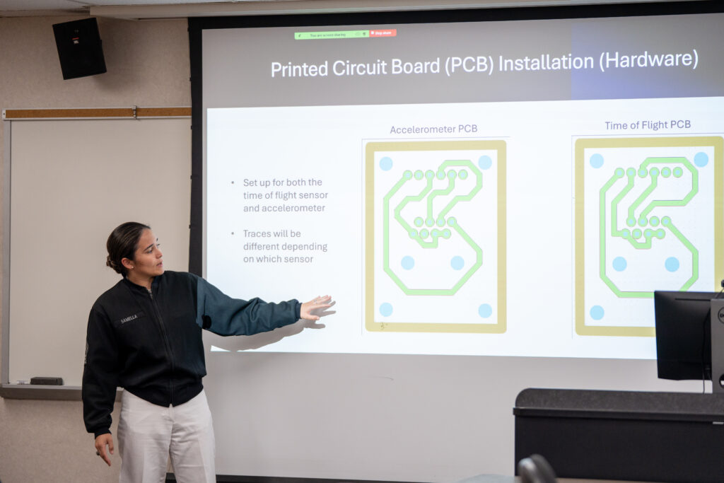 A cadet points to her presentation showing on a projector screen.