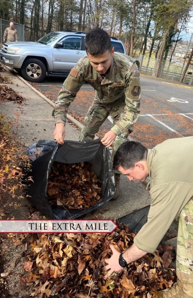 Cadets scoop leaves into a trashbag.