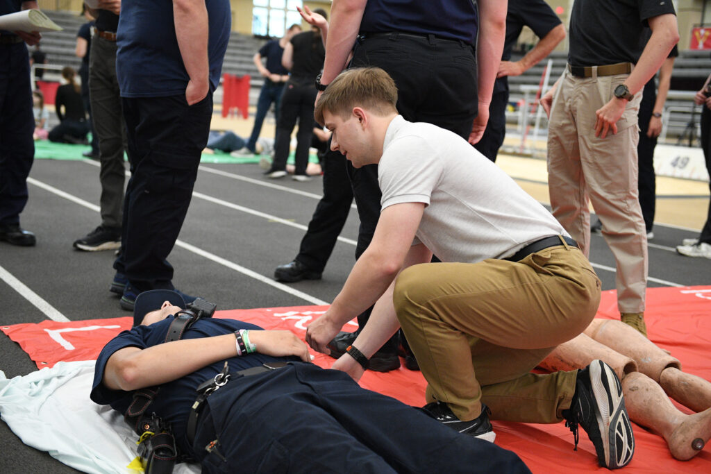 A cadet assesses a human victim as part of mass casualty incident (MCI) training.