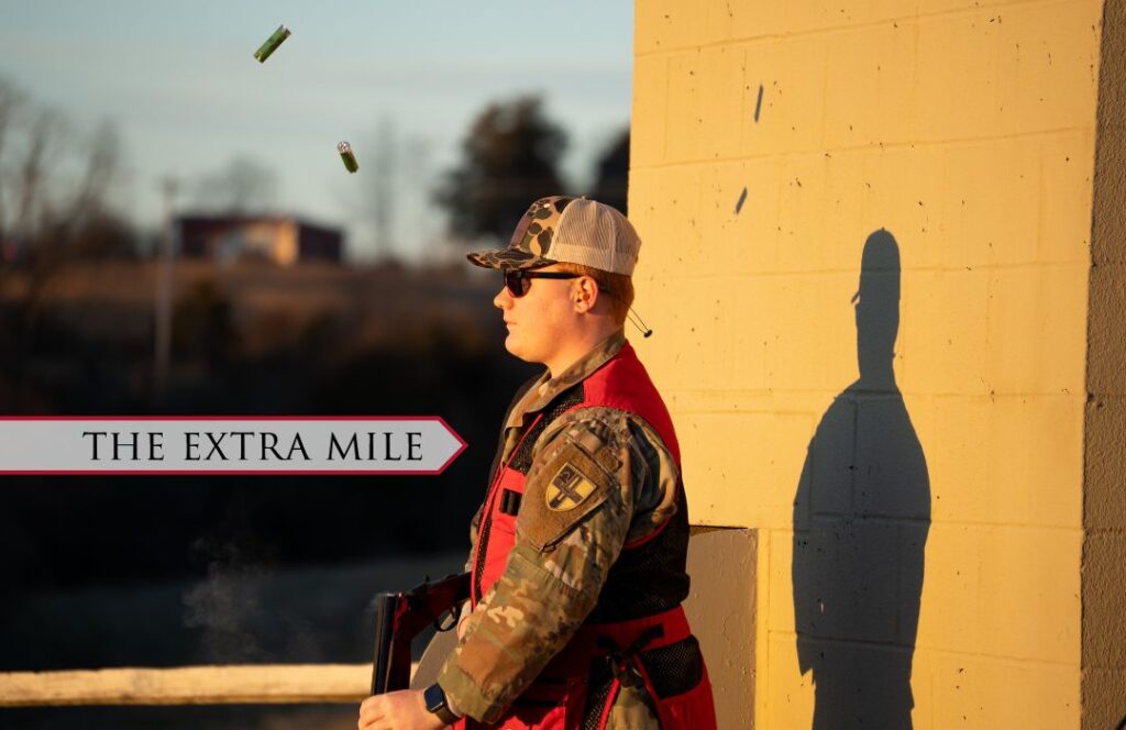 A cadet stands outside a shooting course with bullet shells flying.