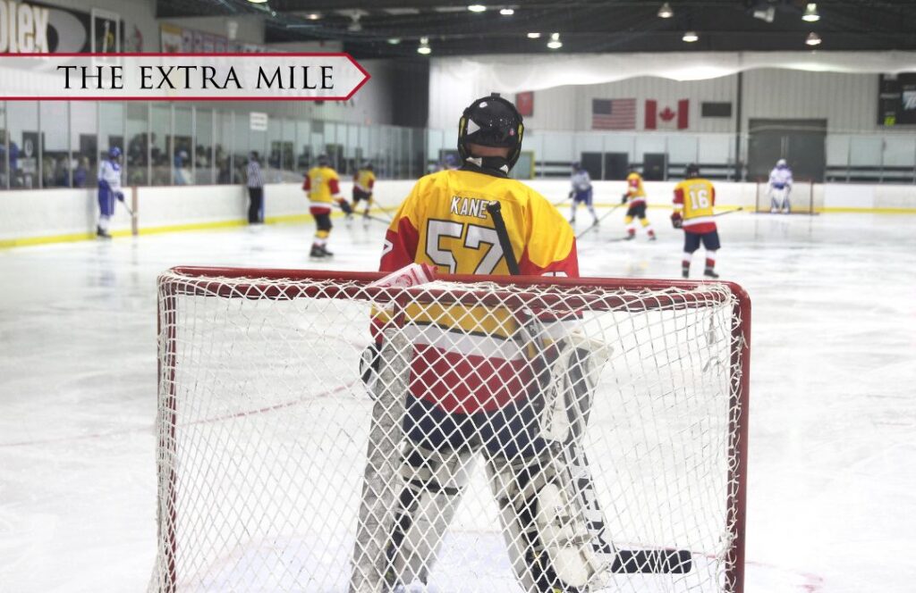 A goalie in front of a net on an ice rink.
