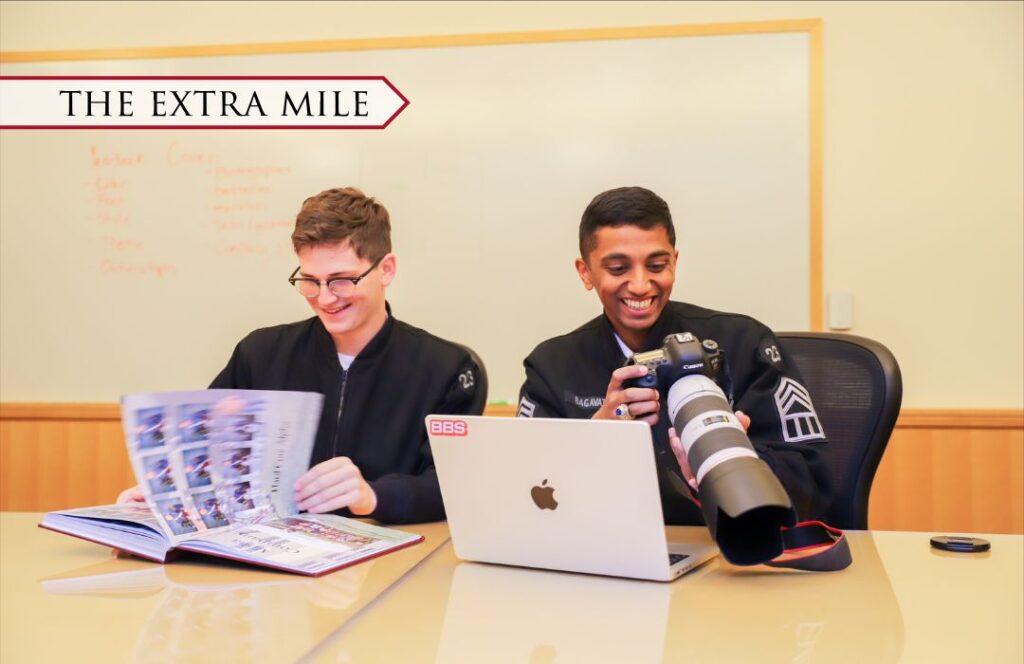 Two students look through a VMI yearbook while editing photos.