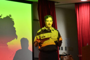 Col. Sunnen stands in front of a screen,