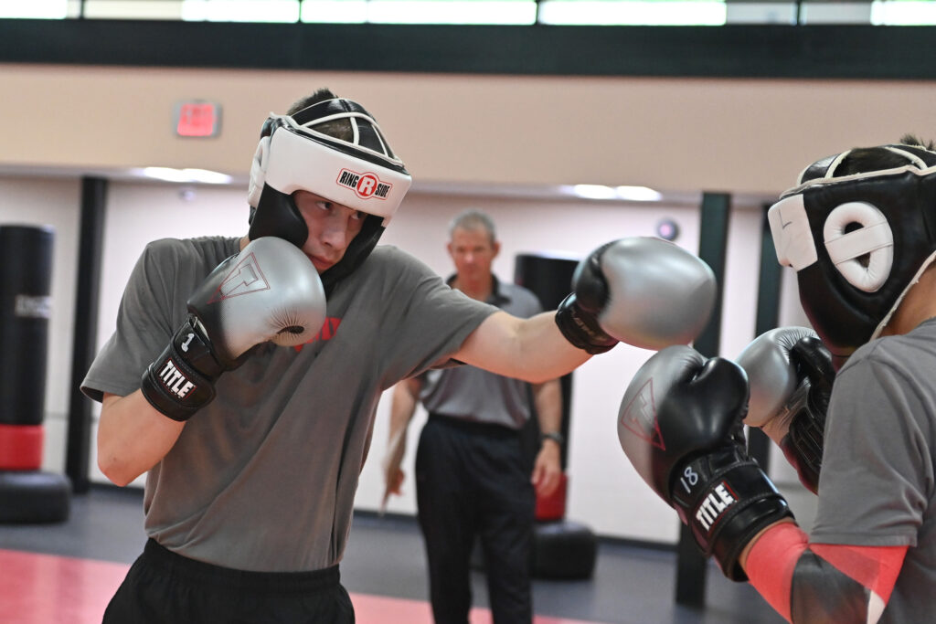 Cadets in boxing gear spar during a class.