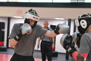 Cadets in boxing gear spar during a class.