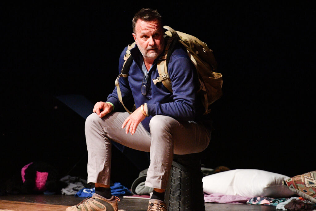 Mann sits on stage with a full pack.