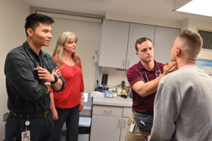 Two alumni medical students work with VMI doctor to examine a cadet.