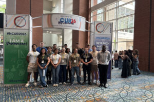 Cadets pose for a photo in front of conference signage.