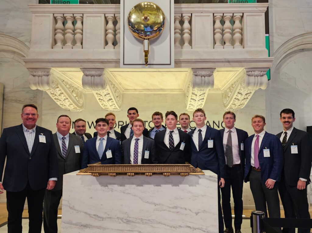 Cadets, professors, and alumni pose for a photo at the New York Stock Exchange.