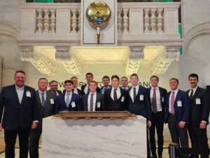 Cadets, professors, and alumni pose for a photo at the New York Stock Exchange.