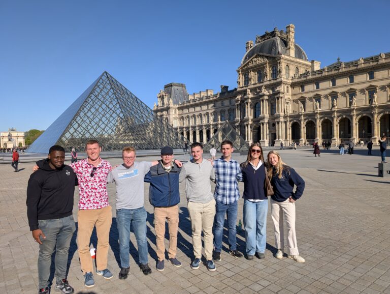 Cadets pose for a photo in front of the Louvre.