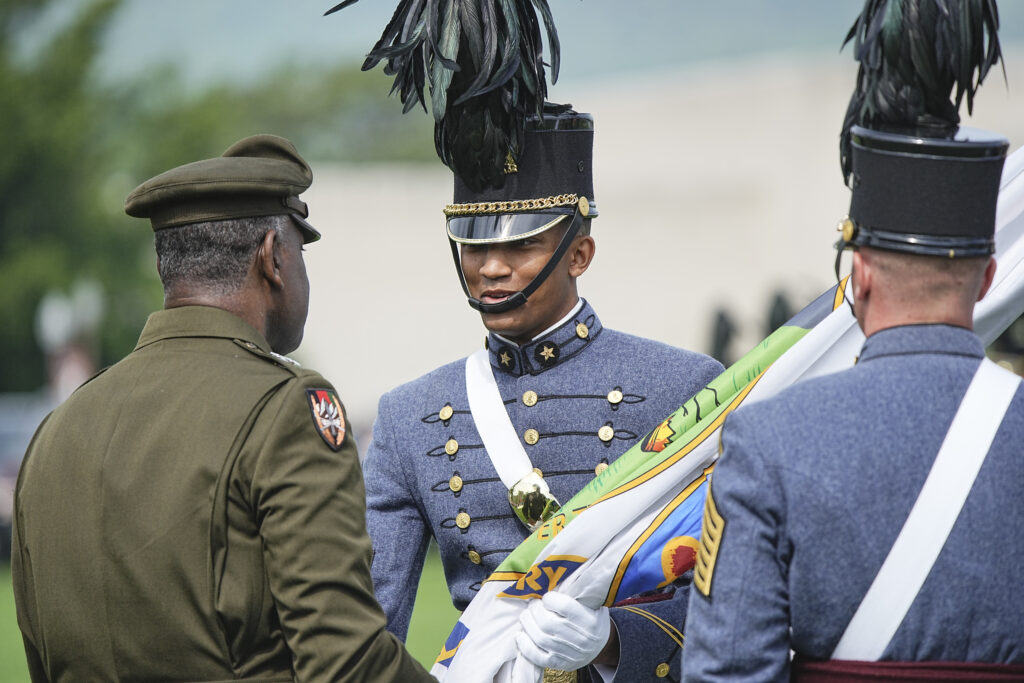 Maj. Gen. Cedric T. Wins '85 hands Devin Auzenne '26 the VMI flag.