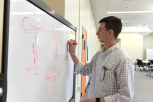 Riley Malone ’25 writing on a white board.