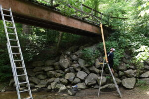 Lawrence Porter '24 sets up equipment to run tests on serviceability of a footbridge on the Cheesie Trail.