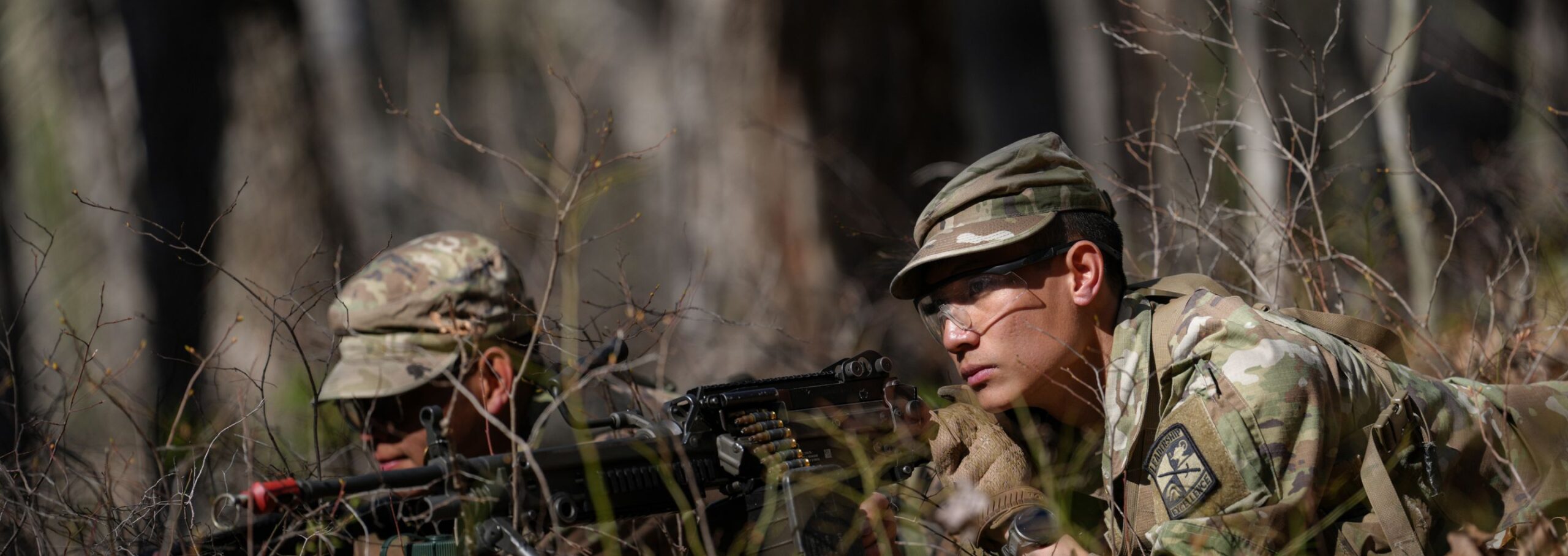 Army ROTC members during a drill activity in the woods.
