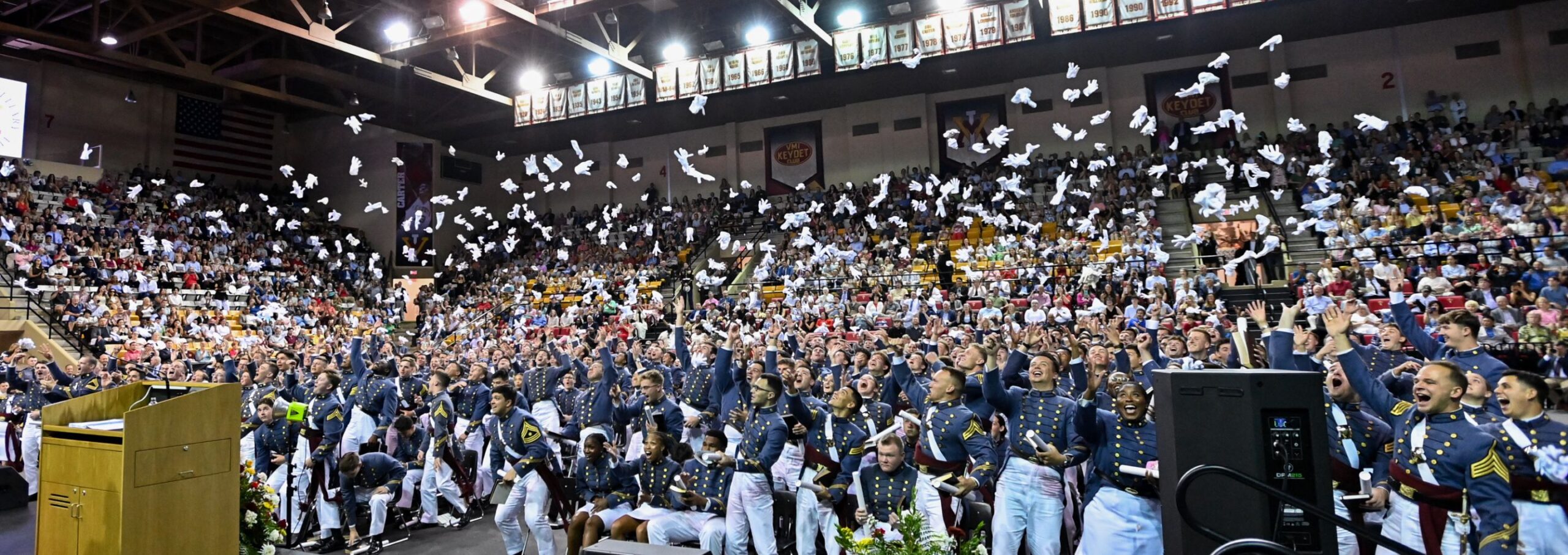 Graduates toss their gloves in the air during commencement.