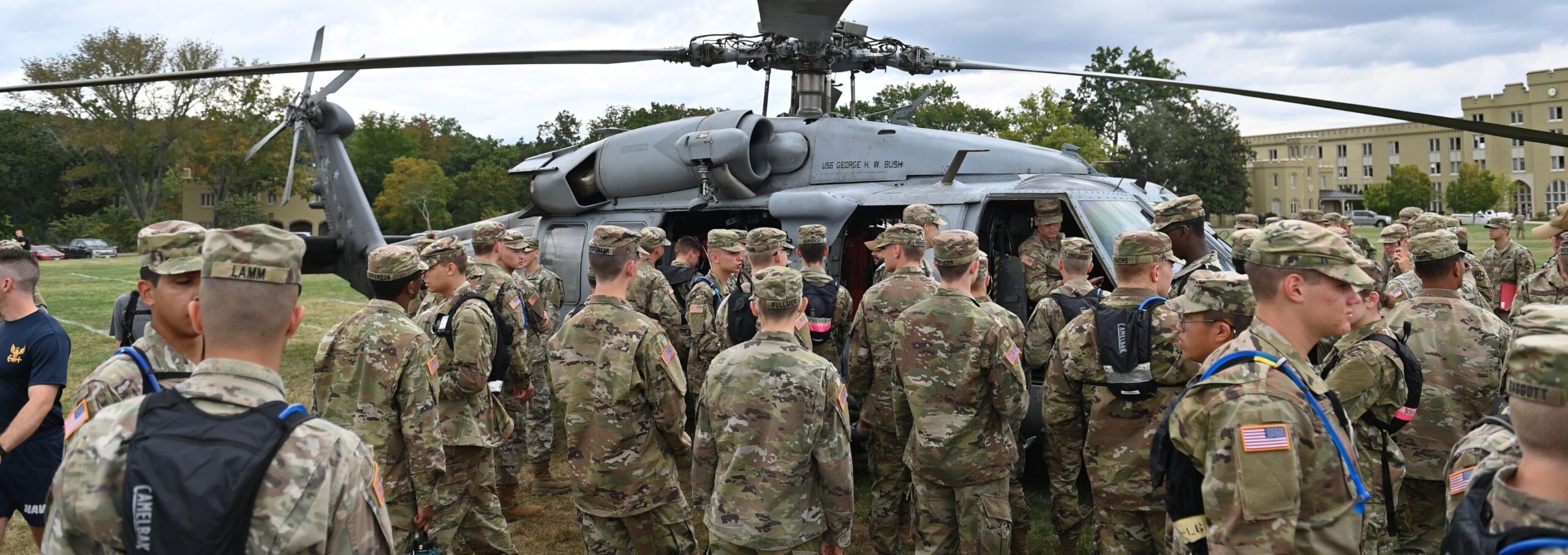 NROTC cadets gather in front of a helicopter.