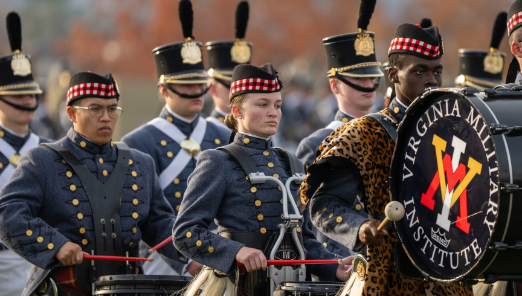 Members of the VMI Pipe and Drums march in full uniform during a military parade.
