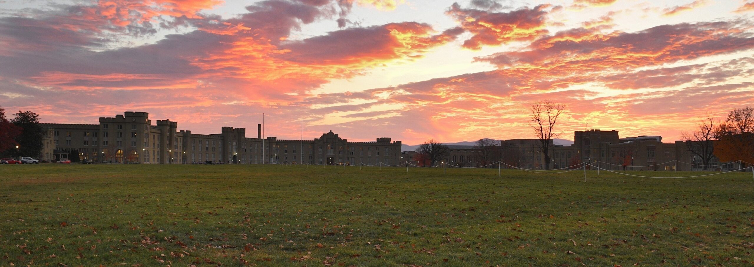 Sunrise over barracks paints the sky in shades of blue, pink, and orange.