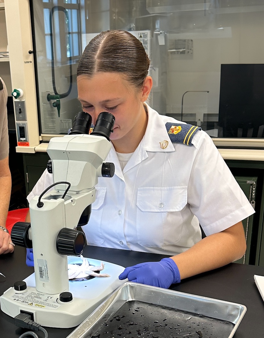 A student in biology examines samples under a microscope.
